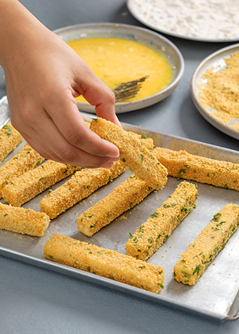 Coloque en una charola los <strong></img>dedos de queso manchego empanizados</strong> y tápelos. Refrigera por 40 minutos.