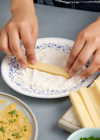 Agrega la taza de <strong>harina</strong> en un recipiente plano y pasa los bastones de queso manchego, trata de cubrirlos totalmente.