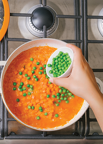 Agrega las zanahorias, chícharos y más caldo. Tapa y cocina hasta que el arroz esté cocido.