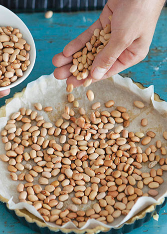 Coloca encima papel encerado y acomoda frijoles crudos para evitar que la masa esponje.