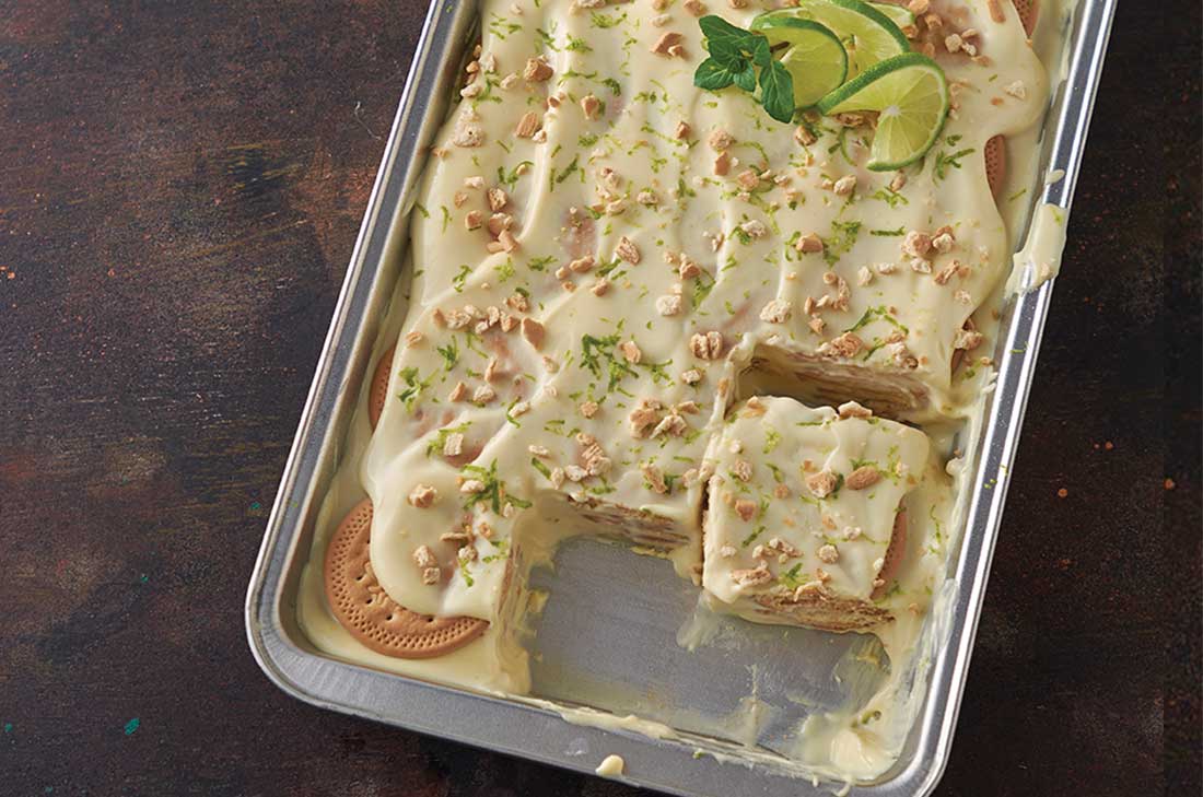 Carlota de limón con galletas marías y queso crema decorada con rodajas y ralladura de limón además de unos trozos de galleta.