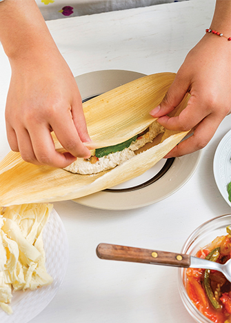 Agrega el queso y cierra la hoja de maíz de un lado y cubre con el resto.