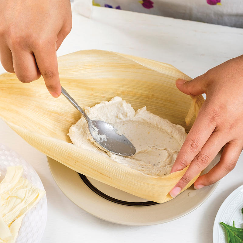 Coloca dos cucharadas de la <strong></img>masa de tamal</strong> al centro de la <strong>hoja de maíz</strong> y haz un ligero hueco.