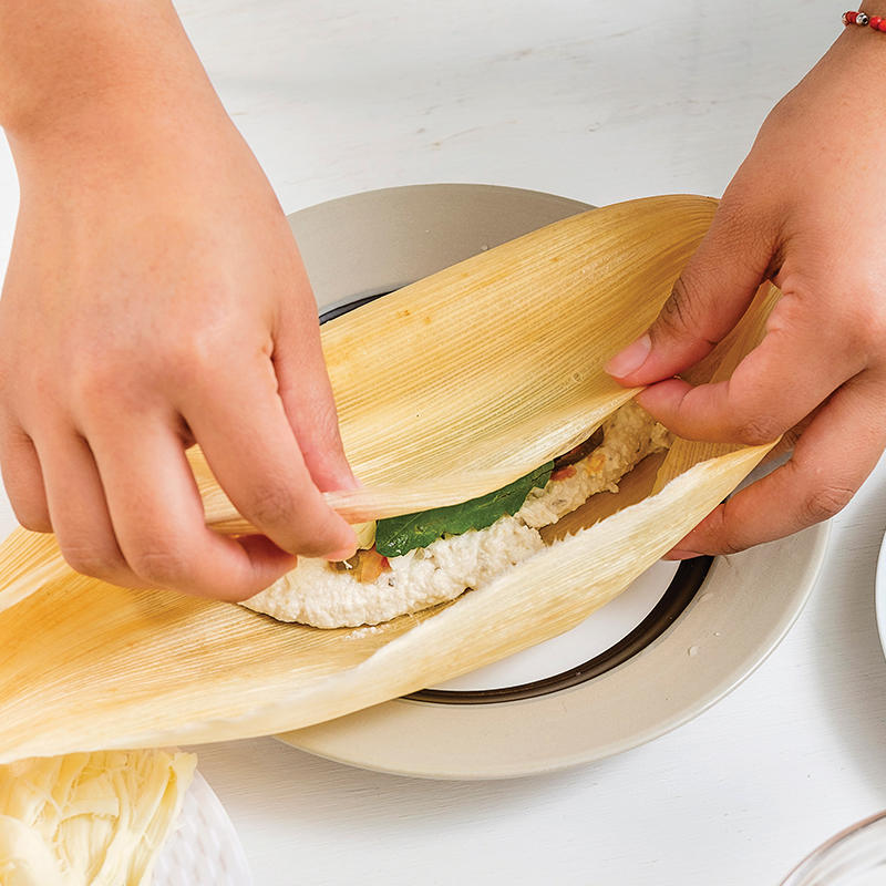 Después sobre esa mezcla agrega el <strong></img>queso oaxaca</strong> y cierra la hoja de maíz de un lado. Cubre con el resto a manera de envoltura.