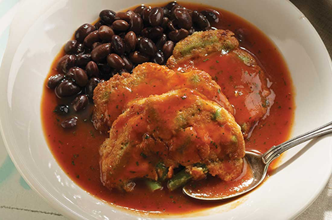 Tortitas de ejote con huevo y queso en caldillo de jitomate con una guarnición de frijoles negros de la olla