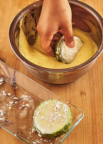 Sumerge la calabacitas en la mezcla de huevo para capearlas.
