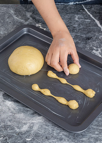 COLOCA las canillas, el pan y la bolita en una <strong></img>charola</strong> previamente engrasada. Deja reposar por unos minutos hasta que crezca de tamaño.