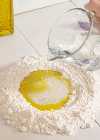 FORMA un volcán con la harina, agrega al centro la sal, el aceite de oliva y la mitad del agua.