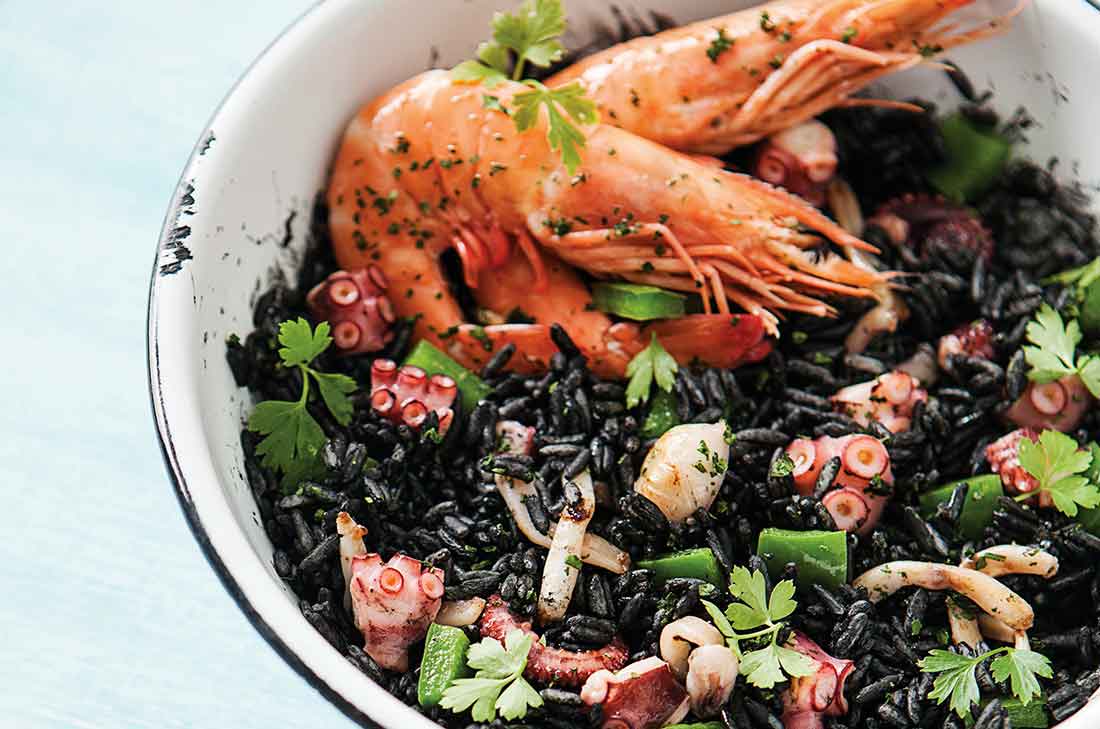 El arroz negro es delicioso por el rico sabor del mar. Disfruta de este rico platillo con calamar, camarones pulpo y pimiento verde.