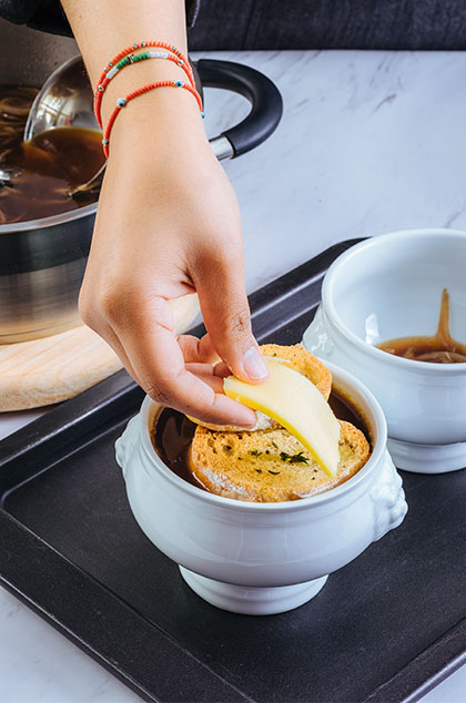 COLOCA una rebanada de pan sobre la sopa y cubre con el queso. Hornea por 10 minutos o hasta que el queso se haya fundido.
