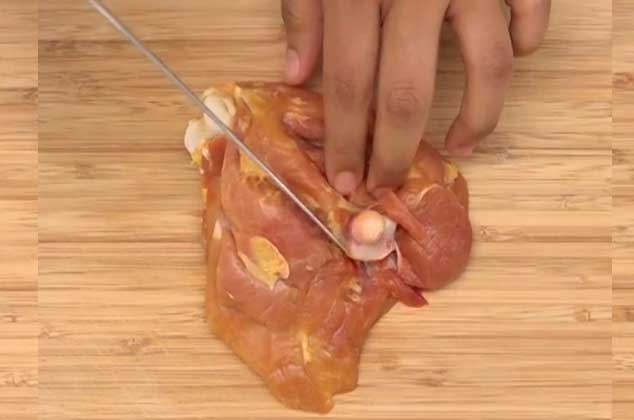 VOLTEA el muslo de pollo, del lado del hueso y comienza a hacer una incisión al ras del hueso de manera superficial