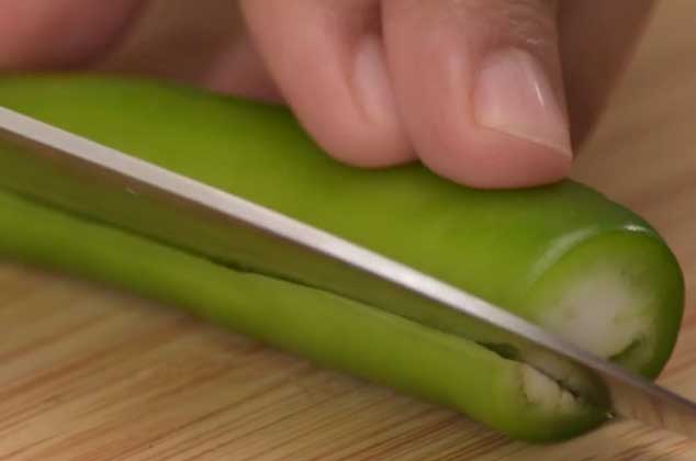 HAZ un corte en un cuarto del chile serrano y comienza a desdoblar la pieza para retirar las semillas. 