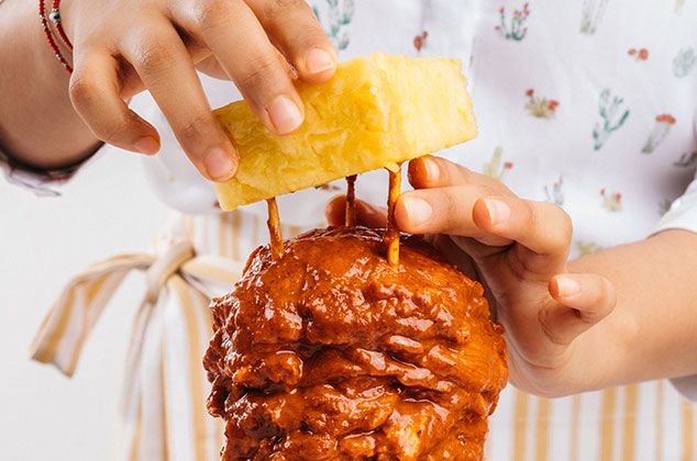 INSERTA la piña al final de la carne. Tapa el trompo con aluminio y hornea por 45 minutos. Destapa y hornea por 15 minutos más.