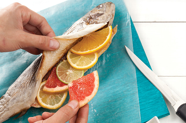 REALIZA un corte a lo largo de las truchas y rellena con la naranja, los limones y la toronja en rodajas.