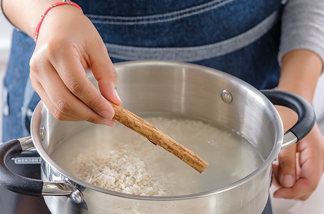 COLOCA el agua en una cacerola. Añade el arroz y la raja de canela.