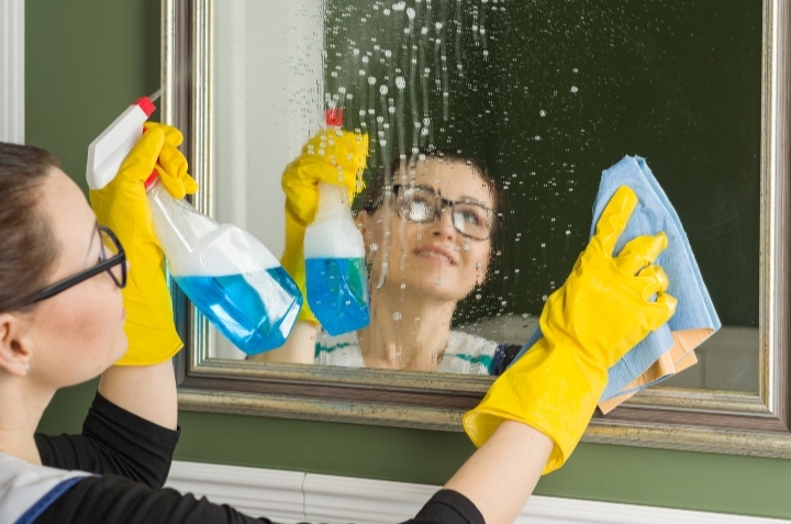 mujer limpiando espejo