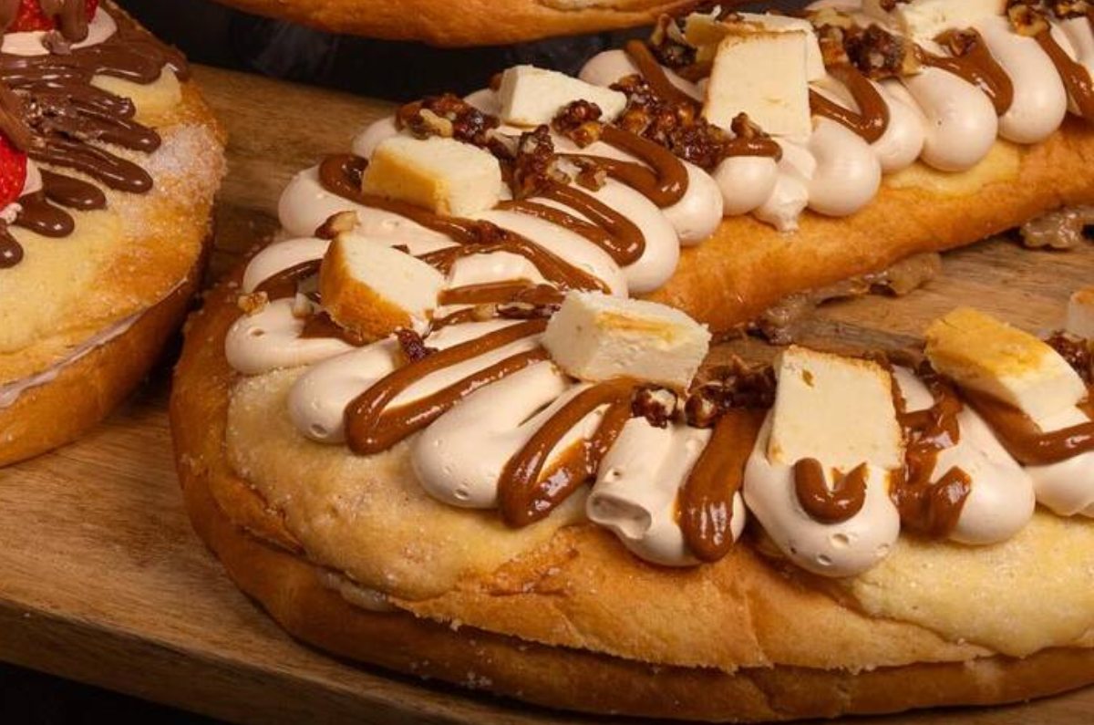 Rosca Pecan y Cheesecake: La rosca está rellena de pie de nuez, decorada con un betún cremoso de caramelo, trocitos de cheesecake, dulce de leche, y nueces caramelizadas.